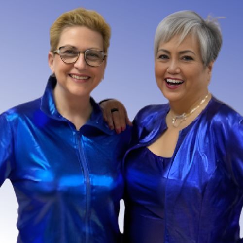 Woman with short blonde hair standing next to a woman with short gray hair, they are both wearing bright blue outfits