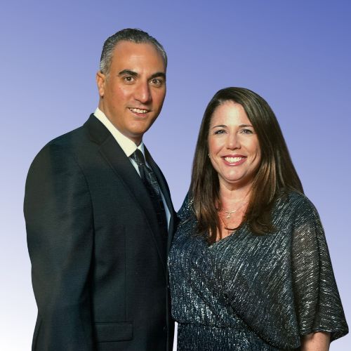 Man with dark hair wearing a black suit and tie and a woman with shoulder length brown hair wearing a black sparkly dress